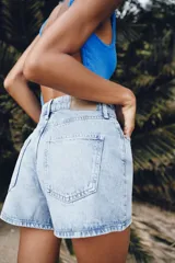 Shorts de denim de tiro medio, corte mom fit, con cinco bolsillos y cierre frontal con cremallera y botón, en color azul lavado.