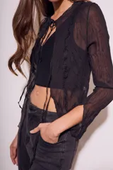 Blusa negra traslúcida de viscosa con textura arrugada, mangas largas acampanadas y escote en V con lazos.