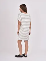 Vestido corto de manga corta, color blanco con rayas horizontales negras, cuello redondo y corte holgado.