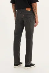Pantalón de jean corte slim fit, color gris oscuro con efecto lavado, de tiro medio y cierre frontal con botón y cremallera.