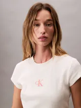 Remera de corte cropped y ajuste ceñido, confeccionada en tejido de algodón con elastano. Presenta cuello redondo, mangas cortas y el monograma de la marca estampado en el centro del pecho.