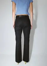 Pantalón de tiro bajo y diseño acampanado color negro, con trabillas para cinturón y bolsillos traseros ribeteados, confeccionado en mezcla de algodón elástico.