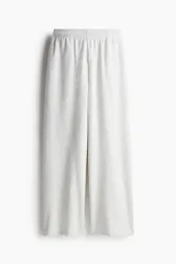 Pantalón de jogging de corte ancho y tiro alto, color gris melange, confeccionado en tejido de felpa con interior cepillado suave. Posee cintura elástica fruncida con cordón de ajuste oculto, bolsillos laterales y un bolsillo trasero abierto.