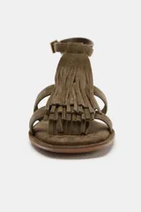 Sandalia plana color verde militar, con tiras de cuero y detalle de flecos en la parte delantera. Tiene pulsera al tobillo con cierre de hebilla metálica y punta redonda.