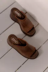Sandalias de plataforma color marrón, con diseño de una sola tira ancha con detalle de costuras expuestas en los bordes y punta cuadrada.