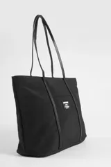 Cartera tipo shopper color beige con asas y detalles decorativos en cuero sintético negro. Cuenta con un bolsillo frontal exterior adornado con una etiqueta rectangular de la marca Symphorine.
