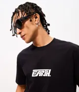 Remera de algodón color negro con cuello redondo y manga corta. Presenta un diseño gráfico estampado en la espalda con la palabra 'EARTH' en tipografía grande y blanca, acompañada de frases motivacionales y símbolos circulares.