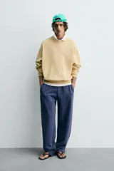 Sudadera de algodón con interior rizo, cuello redondo y manga larga. Presenta un efecto lavado que le da un color amarillo pálido y un estampado frontal en hilo blanco con el texto "west nord 89".