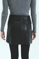 Minifalda negra de ecocuero con textura croco, cierre metálico lateral y tajo en la pierna derecha.