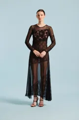 Vestido largo negro de manga larga, confeccionado con una combinación de tela translúcida y encaje floral. Presenta cuello redondo y diseño ajustado.