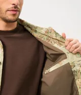 Campera trucker de Marfinno para hombre, con diseño de estampado floral en tejido jacquard texturizado de tonos verdes y beige. Presenta cuello camisero, cierre frontal de botones metálicos y bolsillos en el pecho.
