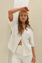 Camisa de lino color beige con diseño bordado y perforado, cuello camisero y mangas cortas.
