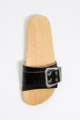 Sandalias de madera con tira ancha de cuero sintético negro con textura de cocodrilo, hebilla metálica plateada y apliques de tachas plateadas.