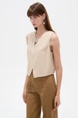 Musculosa cropped de viscosa color rosado, con cuello a la base, pequeña abertura frontal y detalle de hebilla metálica decorativa.