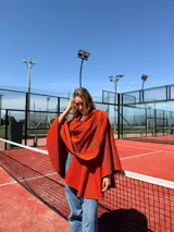 Capa color naranja de lana merino con cuello redondo y diseño con pespuntes en la espalda.