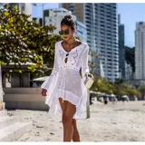 Vestido de playa corto en tejido calado color crema, con mangas largas acampanadas y diseño asimétrico con volado en el ruedo. Presenta un escote redondo con abertura frontal y cordón ajustable.