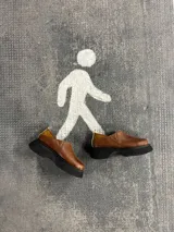 Zapato marrón de cuero con elástico en los laterales y suela de goma negra.