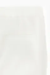 Pantalón sastrero blanco de pernera ancha y recta, con pliegues frontales marcados.