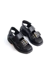 Sandalias negras de cuero con diseño de plataforma dentada, tiras ajustables con hebillas metálicas y detalle de tachas plateadas en el lateral de la suela.