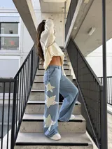 Jeans celestes de corte wide leg, tiro mid-rise, con grandes apliques de estrellas deshilachadas en tono crudo a lo largo del lateral de la pierna.
