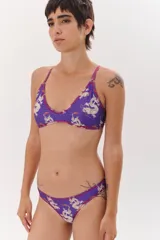 Conjunto de bikini violeta con estampado de dragones, compuesto por un corpiño triangular con tiras cruzadas en la espalda y cordón para atar en el centro, y una bombacha clásica tipo vedetina.