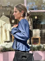 Blusa de manga larga con cuerpo fruncido mediante elásticos y terminación con volados en el ruedo. Presenta un diseño versátil y adaptable.