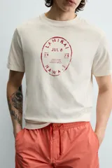 Camiseta de corte regular, color crudo, con cuello redondo y manga corta. Presenta un estampado frontal con diseño circular en tono rojizo con efecto lavado.