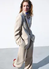 Blazer Paola de corte recto, color beige, confeccionado en mezcla de lana y lino. Presenta cuello pico con solapa, mangas largas, un bolsillo de ribete en el pecho, dos bolsillos con solapa en los laterales y cierre frontal de un botón oscuro.