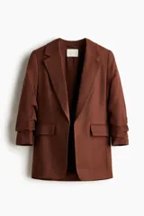 Blazer entallada color marrón, confeccionada en mezcla de viscosa. Cuenta con hombreras, solapas de muesca, mangas tres cuartos fruncidas y bolsillos delanteros con solapa. Diseño sin cierre y totalmente forrado.