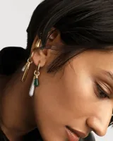 Aro individual dorado con forma de argolla y dije colgante en forma de gota.