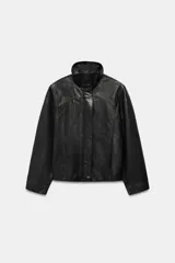 Cazadora de corte oversize confeccionada en 100% piel. Presenta cuello subido, manga larga con hombro caído y cierre frontal mediante cremallera y botones a presión ocultos bajo una solapa. Incluye bolsillos laterales ocultos en las costuras y forro interior.