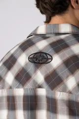 Camisa de manga corta de popelina cuadrillé en tonos marrón, blanco y gris, con diseño boxy fit, cuello camisero, cierre frontal de botones, bolsillo en el pecho con detalle bordado y dobladillo recto.