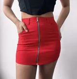 Minifalda roja de corte ajustado, con bolsillos delanteros y cierre metálico frontal.