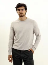 Sweater de punto color beige, con cuello redondo y mangas raglán.