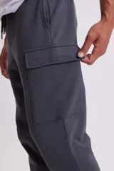 Pantalón estilo jogger en color gris oscuro, con diseño cargo que incluye bolsillos laterales amplios. Cuenta con cintura elástica con cordón ajustable y puños acanalados en los tobillos.