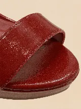 Sandalias de plataforma y taco alto de charol negro, con tira delantera ancha, tira ajustable al tobillo con hebilla dorada y talón cerrado.