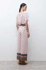 Pantalón de corte recto y tiro alto con estampado geométrico en tonos rojos y negros sobre fondo crudo. Presenta un borde inferior con diseño ornamental y bolsillos laterales.