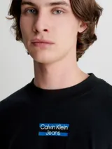 Remera de manga larga Calvin Klein Jeans, color negro, con corte oversized y cuello redondo. Presenta un logo estampado en el centro del pecho sobre una franja horizontal azul.