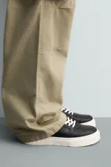 Zapatilla deportiva de estilo retro con parte superior de cuero sintético y suela de plataforma con diseño irregular y texturizado.