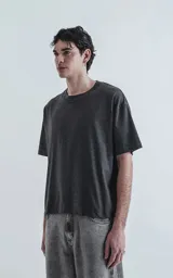 Remera de manga corta y cuello redondo, color gris melange oscuro, con corte boxy fit, ligeramente más corta y mangas amplias.