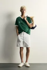 Polo de fútbol retro color verde oscuro, de corte regular fit, con cuello solapa blanco, mangas cortas con ribetes blancos y bandas en los hombros. Cuenta con estampado frontal del número 80 y un gráfico con efecto lavado.