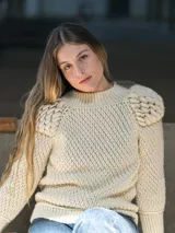 Sweater tejido a crochet color crudo, con cuello redondo, mangas largas y hombros abullonados.