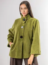 Chaqueta tipo capa confeccionada en paño, con cuello alto, cierre frontal de botones grandes y mangas amplias. Cuenta con bolsillos laterales y forro interior.