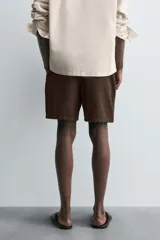 Bermuda de algodón color beige claro, de corte regular fit, con cintura elástica ajustable mediante cordón. Presenta bolsillos laterales y un bolsillo trasero de vivo.