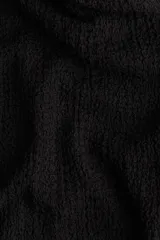 Top corto negro de un hombro en punto con textura. Modelo de ajuste ceñido con escote asimétrico y hombro de diseño girado con detalle metálico dorado adelante. Frunces laterales y bajo recto.