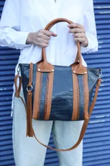 Cartera tipo tote de cuero vacuno con textura crocco en color azul, combinada con detalles en cuero color camel y whisky. Cuenta con doble asa de mano, correa larga ajustable y extraíble, y un detalle de borla decorativa con argolla metálica.
