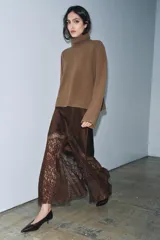 Falda midi de tiro alto confeccionada en tejido satinado color marrón. Presenta un diseño evasé con aplicación de encaje en el lateral y el bajo, y cierre lateral con cremallera oculta.
