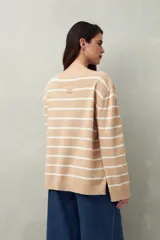 Sweater de punto color crema con rayas horizontales azul marino, cuello redondo y corte recto.