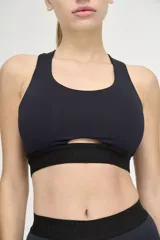 Top deportivo negro con escote redondo, espalda deportiva y abertura geométrica en el centro del pecho.