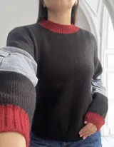Sweater negro de punto con cuello y puños acanalados en color rojo. Mangas largas con detalle de denim.